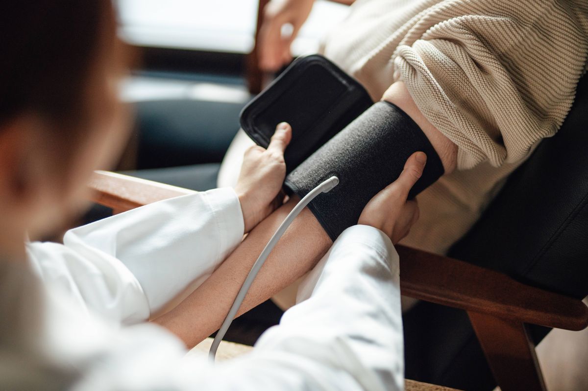 Healthcare worker assisting mature woman to examine blood pressure at home. Healthcare equipment and technology.