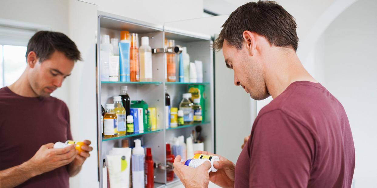 Man looking at bottles from medicine cabinet