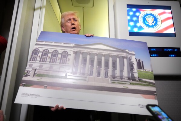 President Donald Trump holds a rendering of the proposed new East Wing of the White House as he speaks to reporters aboard Air Force One en route from West Palm Beach, Fla., to Joint Base Andrews, Md., Sunday, March 29, 2026. (AP Photo/Mark Schiefelbein)