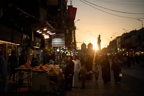 People visit a market near the Kadhimiya Shrine at sunset in the Shiite neighborhood of Baghdad, Iraq, Tuesday, March 31, 2026. (AP Photo/Leo Correa)