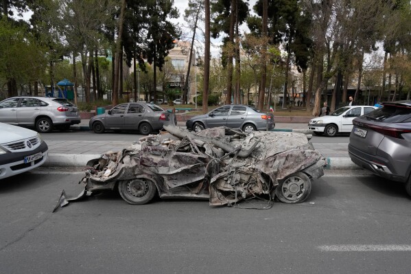 A damaged car is slotted between other vehicles after it was relocated from the area of a residential building that was hit in a U.S.-Israeli strike in Tehran, Friday, March 27, 2026. (AP Photo/Vahid Salemi)