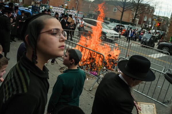 People stand near a fire during "biur chametz," a Jewish ritual where leavened food items are burned on the morning ahead of Passover, Wednesday, April 1, 2026, in New York. (AP Photo/Ryan Murphy)