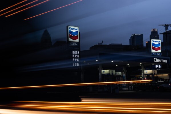 In this photo made with a slow shutter speed, a truck passes by gas prices that are displayed at a Chevron gas station, in downtown Los Angeles, Tuesday, March 31, 2026. (AP Photo/Jae C. Hong)
