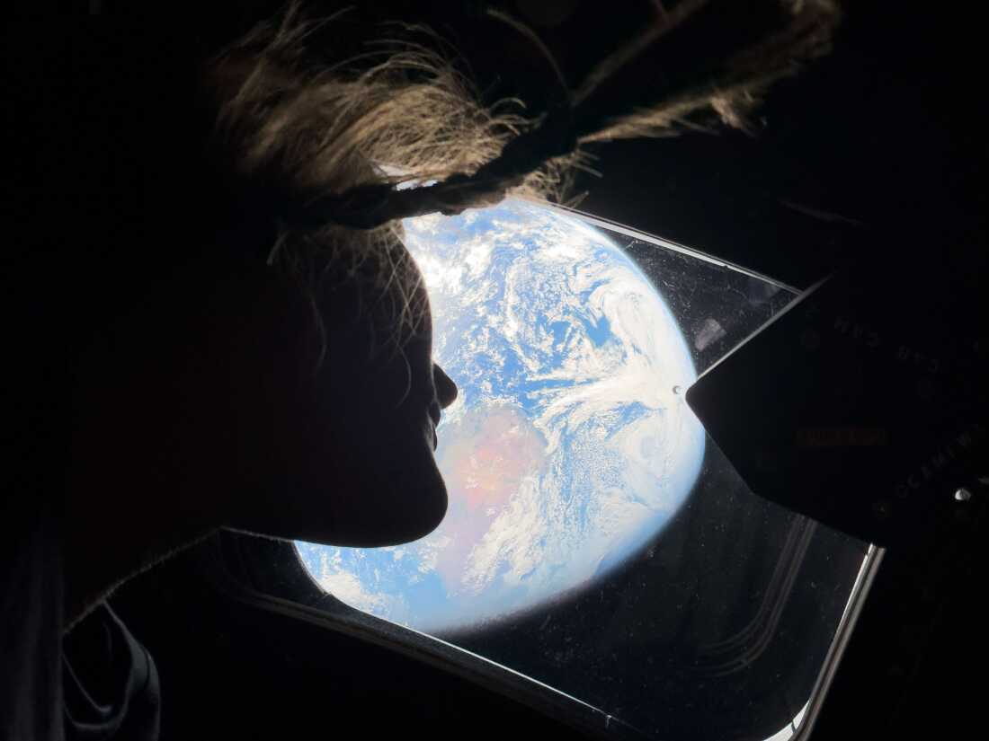 NASA astronaut and Artemis II mission specialist Christina Koch peers out of one of the Orion spacecraft's main cabin windows, looking back at Earth, as the crew traveled towards the Moon on Sunday.