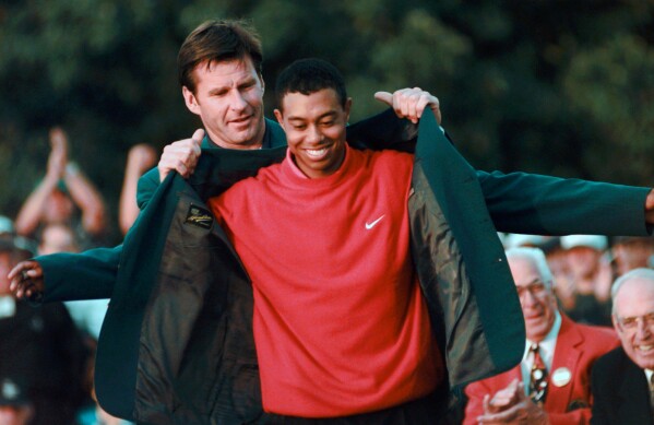Masters champion Tiger Woods receives his Green Jacket from last year's winner Nick Faldo, left, at the Augusta National Golf Club, April 13, 1997, in Augusta, Ga. (AP Photo/ Dave Martin, File)