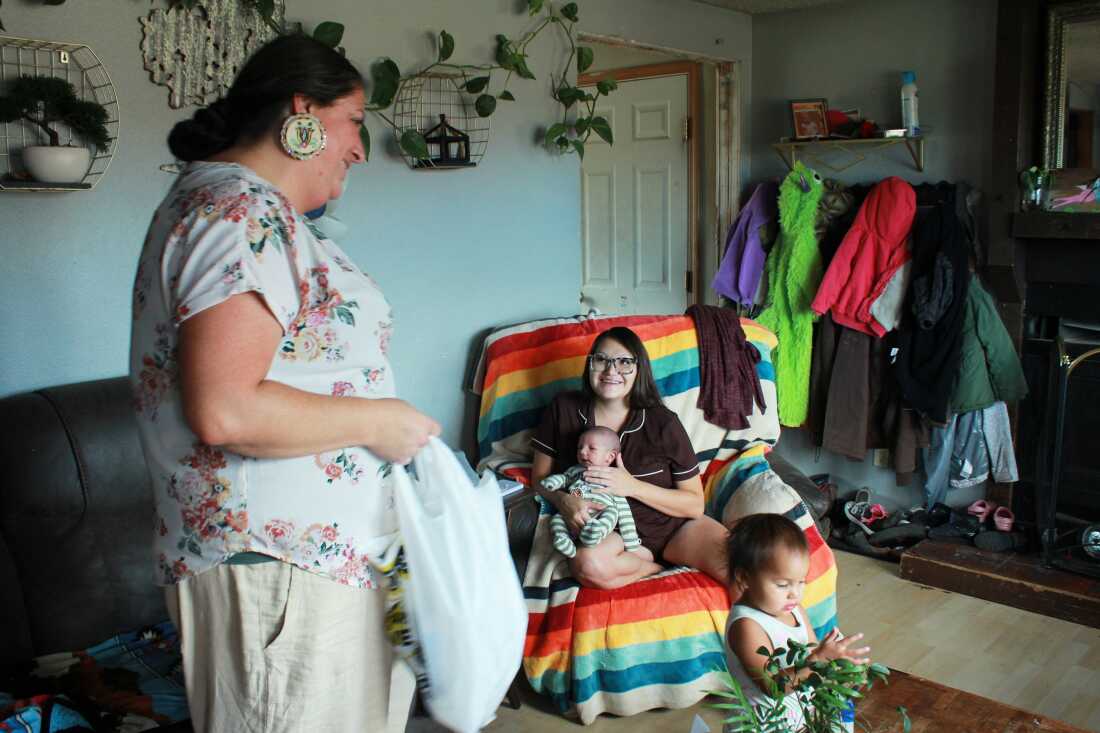 Misty Pipe (left) delivers a care package for a mom she recently supported through pregnancy, Britney WolfVoice. Pipe offers free doula care because Lame Deer — her hometown on the Northern Cheyenne Indian Reservation in Montana — is about 100 miles from the closest hospital that delivers babies.