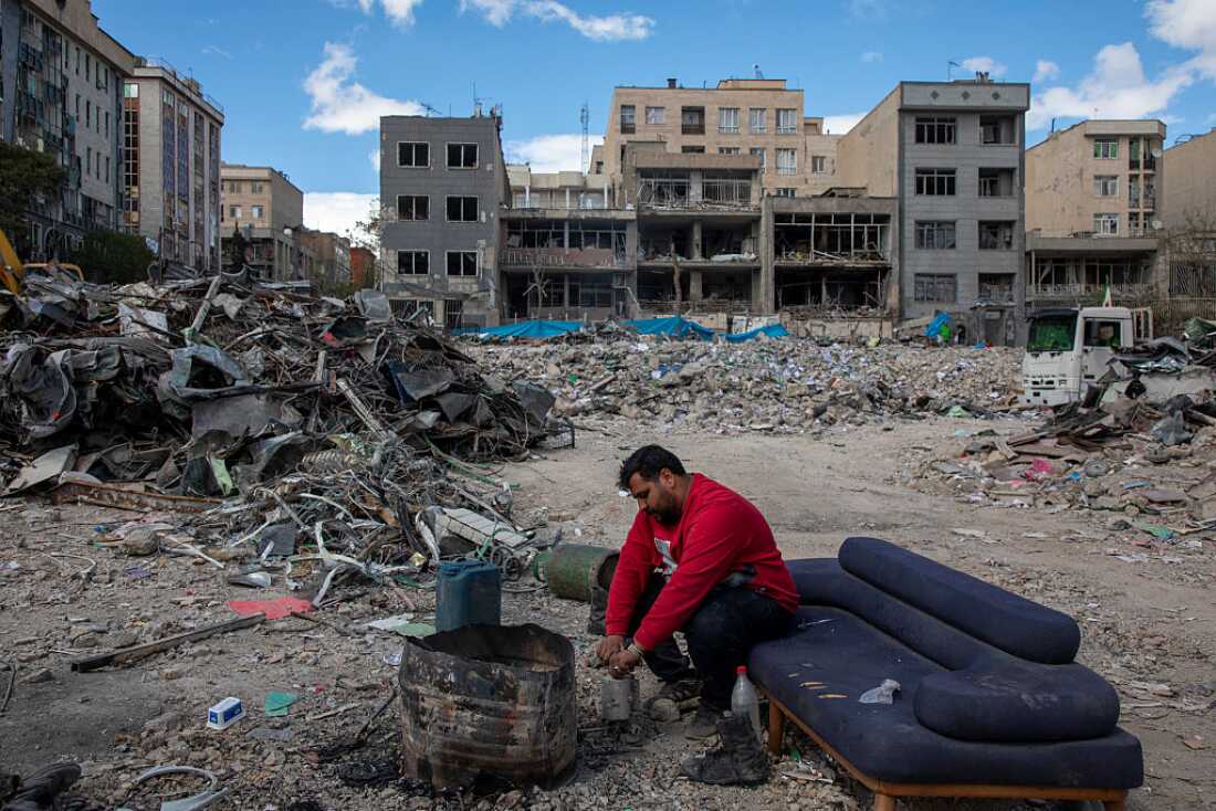 A man sits among buildings destroyed in a joint attack by Israel and the United States on April 6, 2026, in Tehran, Iran.