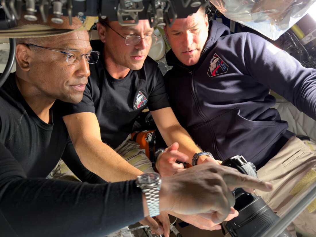 (From left) Artemis II pilot Victor Glover, commander Reid Wiseman and mission specialist Jeremy Hansen prepare for their journey around the far side of the moon by configuring their camera equipment shortly before beginning their lunar flyby observations.