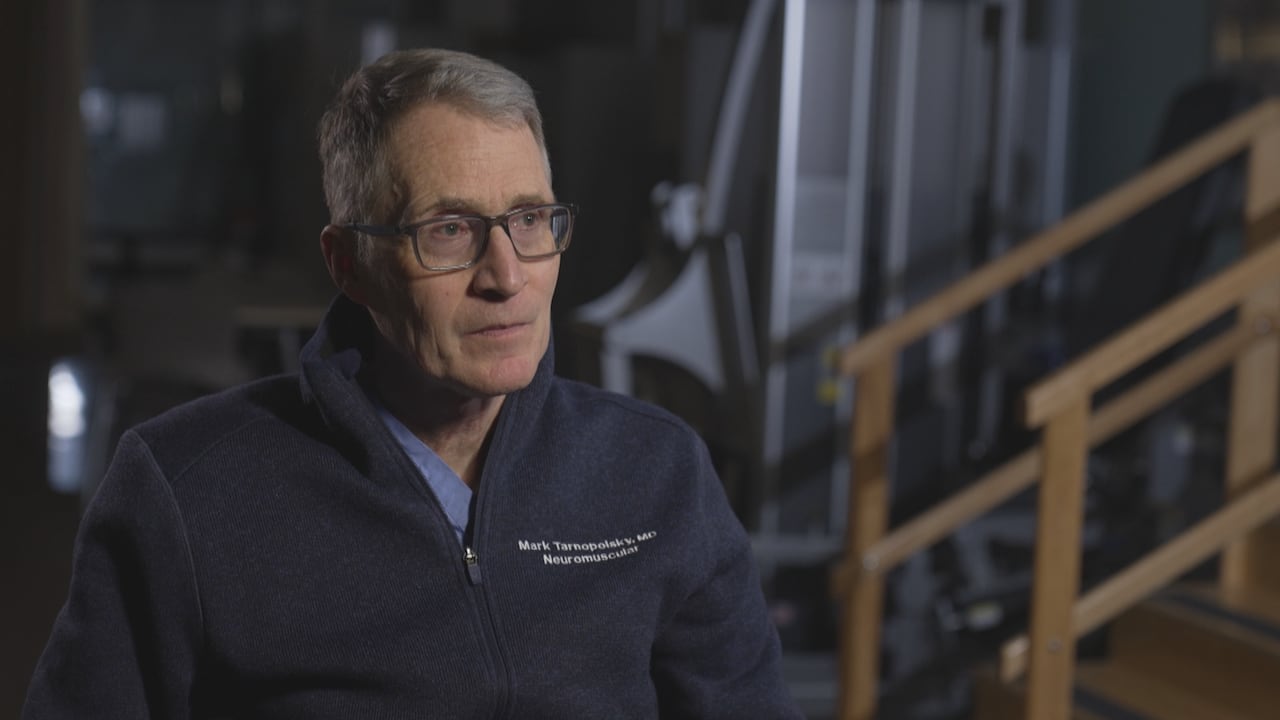 A man wearing glasses and sitting down, looks off camera. 