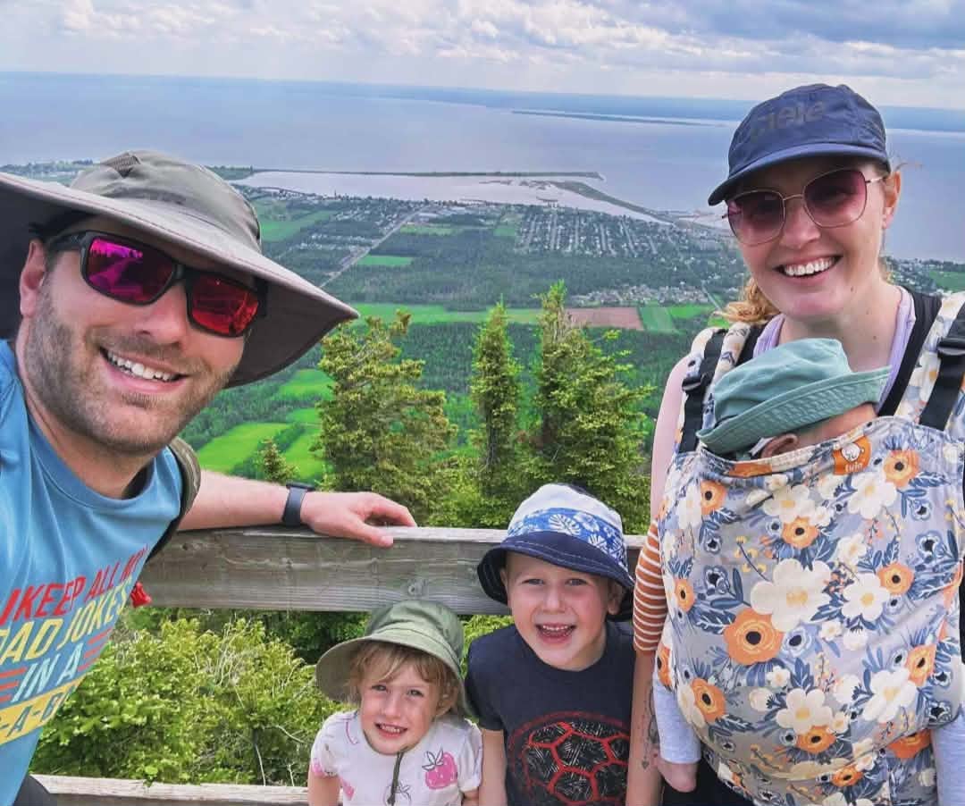 A woman smiles with three children and a man.
