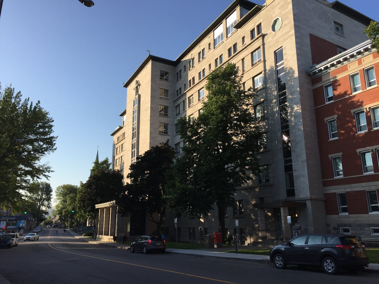 A building on a busy street with trees in the front