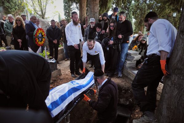 Mourners carry the flag-draped bodies of three members of the Gershovich family, killed when an Iranian missile struck their building, during their funeral in Haifa, Israel, Tuesday, April 7, 2026. (AP Photo/Ariel Schalit, File)