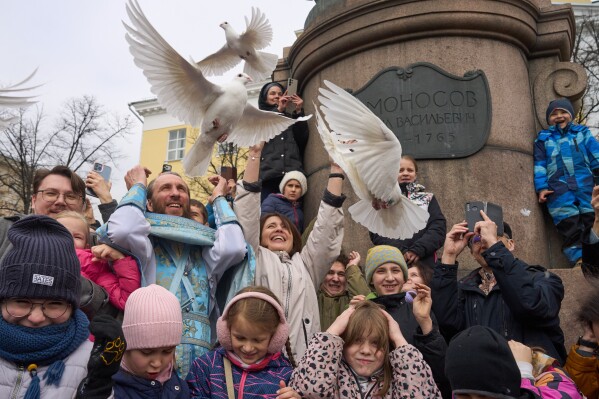 Orthodox priest Father Simeon, center left, with children and their parents, releases birds celebrating the Annunciation preceding the celebration of Orthodox Easter, in front of the Lomonosov Moscow State University and the St. Tatiana Church near the Kremlin, in Moscow, on Tuesday, April 7, 2026. (AP Photo/Alexander Zemlianichenko, File)