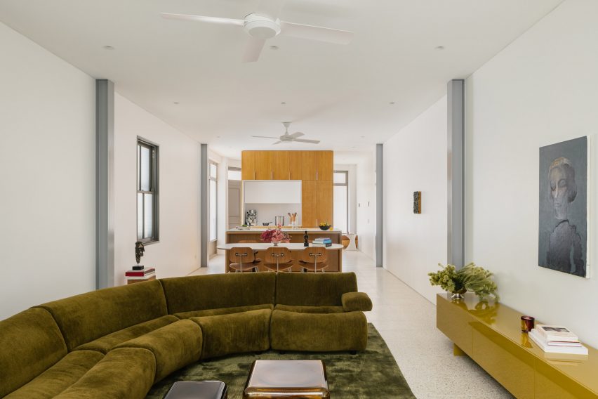 A spacious living room with green sectional and terrazzo flooring in The Corner Hous