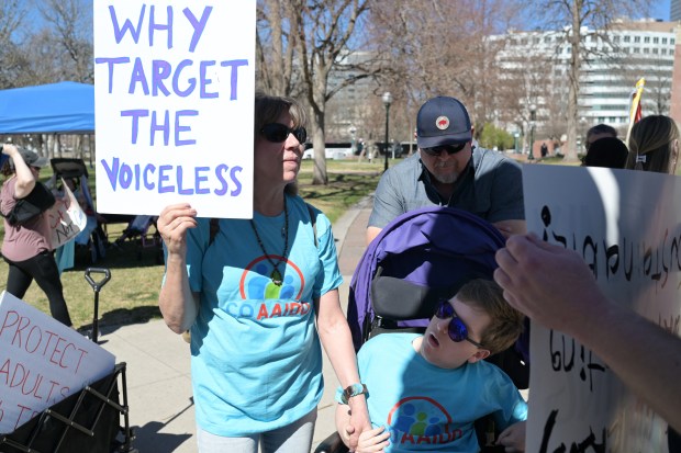 Wendy Lamm, of Castle Rock, left, and her husband, Stephen, right, and their son, Evan, join other families of people with developmental disabilities to protest cuts to their Medicaid services at Civic Center Park in Denver on Wednesday, March 25, 2026. (Photo by Hyoung Chang/The Denver Post)