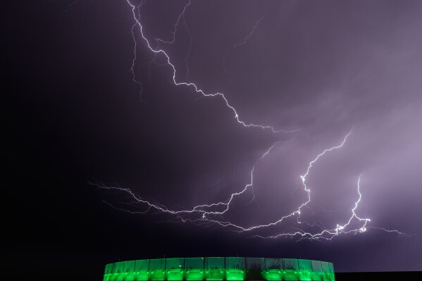 Lightning flashes beyond an office building as a thunderstorm passes in the distance, Monday, April 13, 2026, in Lenexa, Kan. (AP Photo/Charlie Riedel, File)
