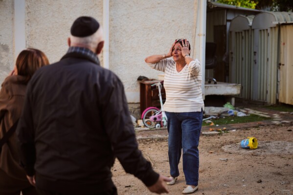 A woman reacts at the site of a damaged residential building after it was struck by a projectile fired from Lebanon, in Nahariya, northern Israel Monday, April 13, 2026. (AP Photo/Ariel Schalit, File)