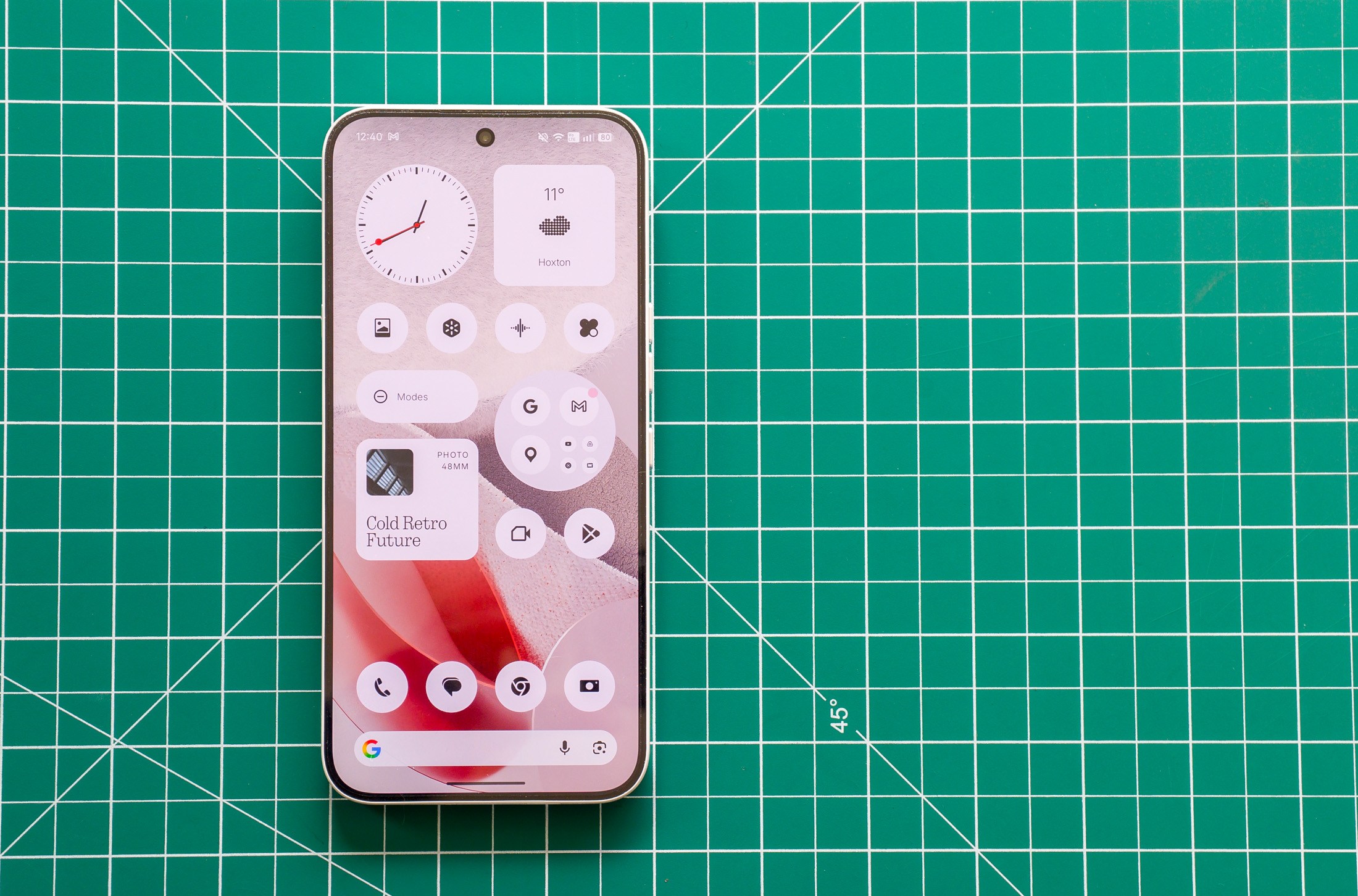 Photo of Nothing Phone 4A Pro on a green cutting mat showing the homescreen