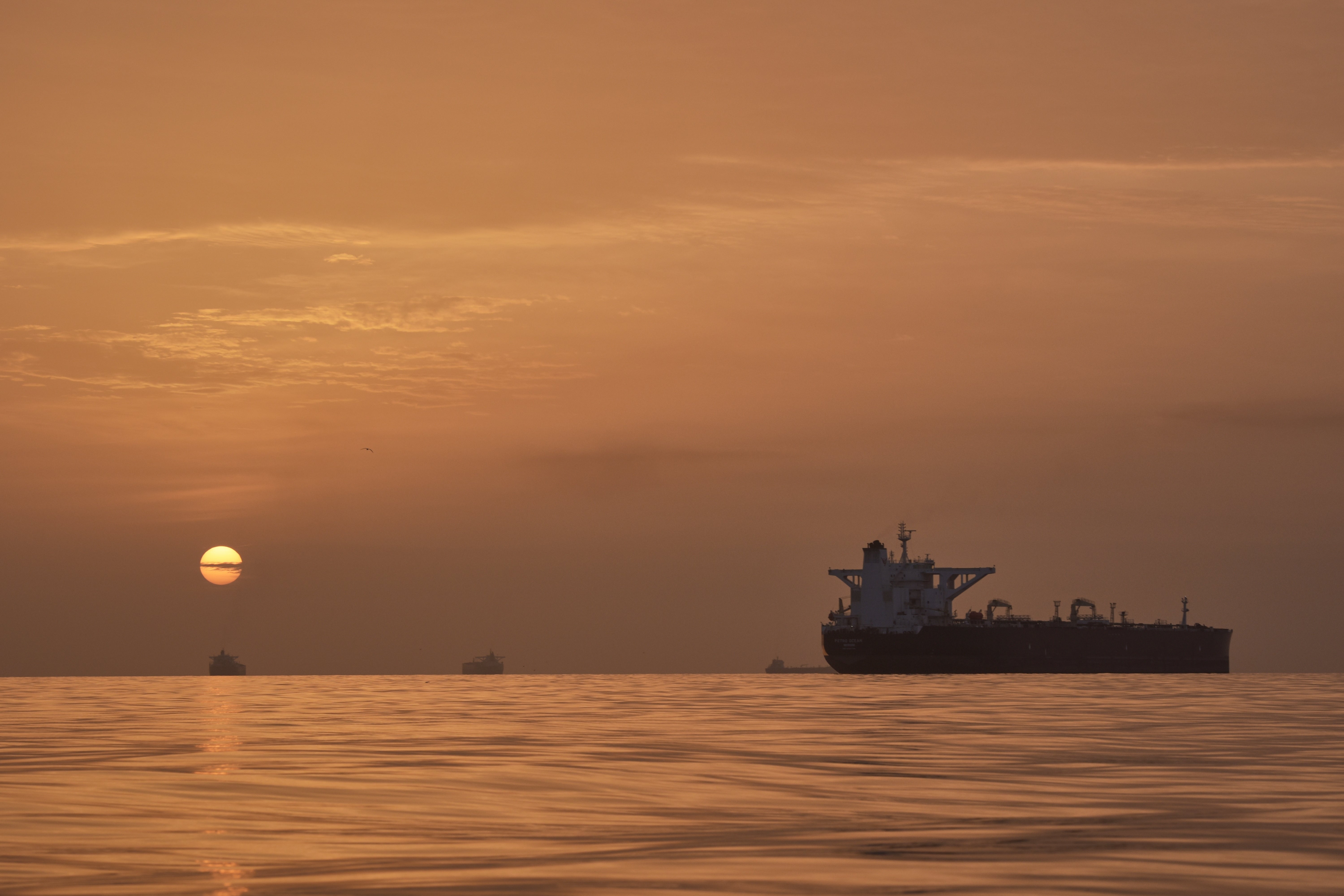 The sun rises behind tankers anchored in the Strait of Hormuz off the coast of Qeshm Island, Iran, Saturday, April 18