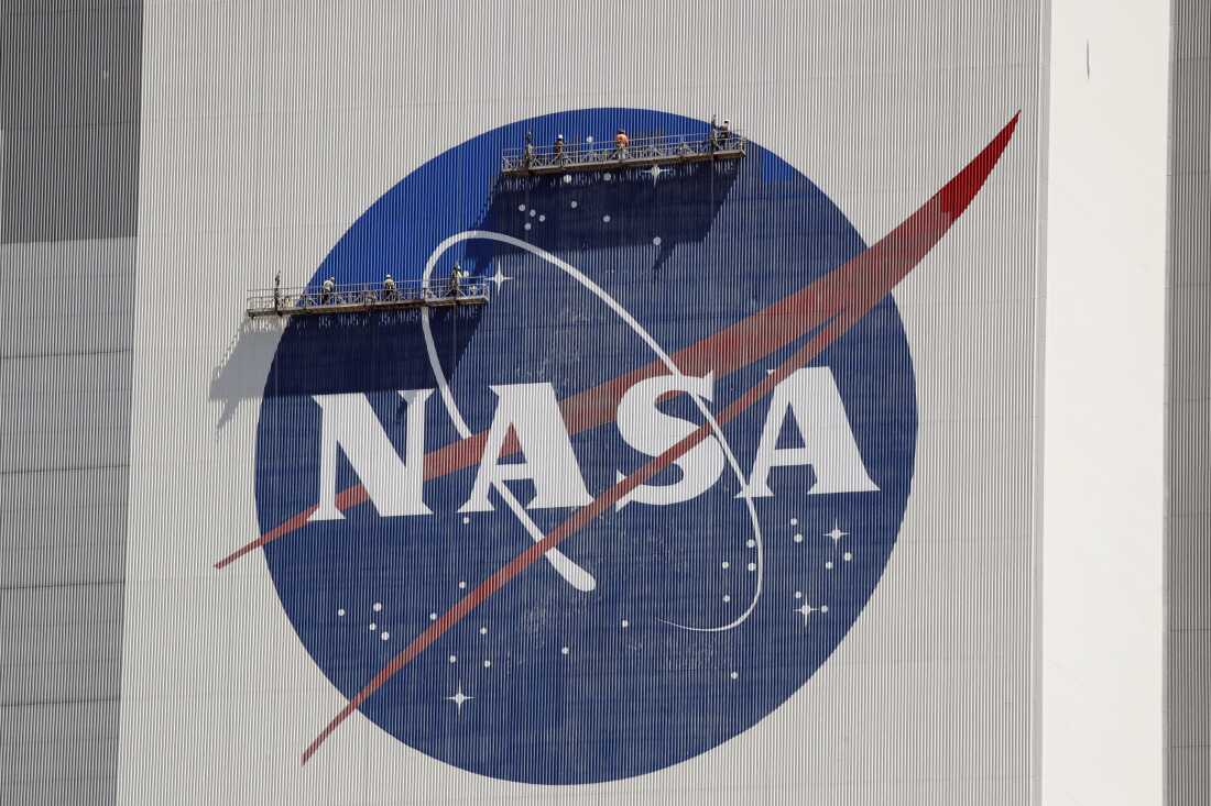Workers near the top of the 526 ft. Vehicle Assembly Building at the Kennedy Space Center spruce up the NASA logo standing on scaffolds in Cape Canaveral, Fla., Wednesday, May 20, 2020.