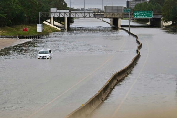 A vehicle is stranded in high waters on a flooded highway at Interstate 10 and Washington in Houston, July 8, 2024, after Hurricane Beryl came ashore. (AP Photo/Maria Lysaker, File)
