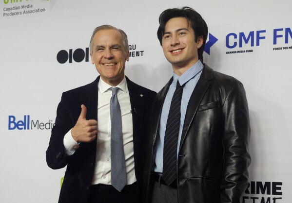 Canadian Prime Minister Mark Carney, left, poses for a photo on the red carpet with Hudson Williams, of the TV series "Heated Rivalry," at the Prime Time screen and media industry conference gala in Ottawa, Ontario, Thursday, Jan. 29, 2026. (Patrick Doyle/The Canadian Press via AP)