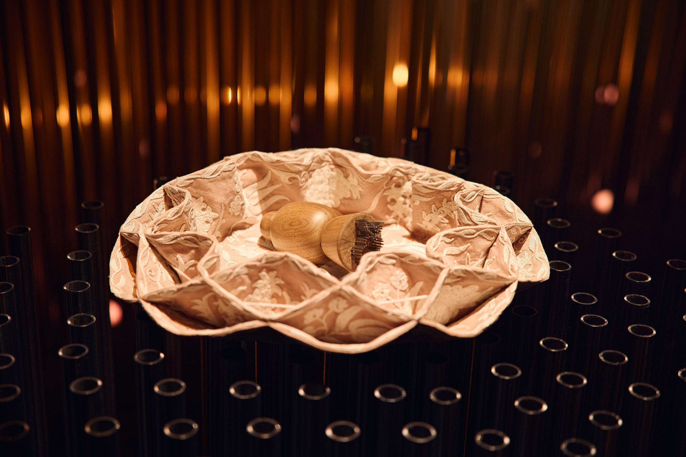 Decorative bread tray lined with patterned fabric displayed on a plinth within the exhibition