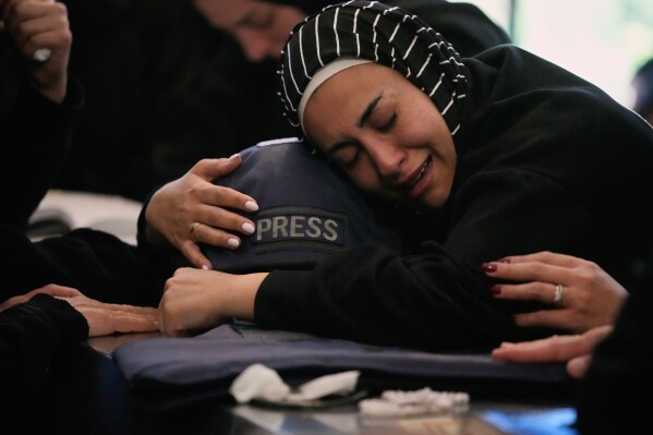 Zainab, the sister of Lebanese journalist Amal Khalil, who was killed on Wednesday in an Israeli airstrike, hugs her helmet as she mourns over her coffin in the village of Baysariyeh, southern Lebanon, Thursday, April 23, 2026. (AP Photo/Mohammed Zaatari, File)