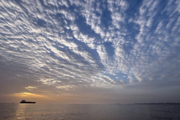 The sun rises behind a tanker anchored in the Strait of Hormuz off the coast of Qeshm Island, Iran, Saturday, April 18, 2026. (AP Photo/Asghar Besharati, File)