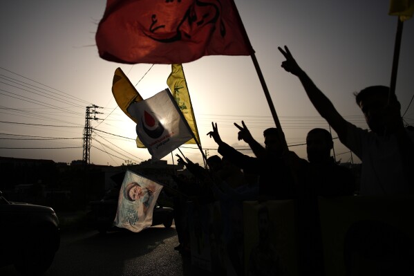People wave Hezbollah flags and an image of late Hezbollah leader Hassan Nasrallah, in Zefta, southern Lebanon, Friday, April 17, 2026, as displaced residents drive back to their villages following a ceasefire between Israel and Hezbollah. (AP Photo/Hassan Ammar, File)