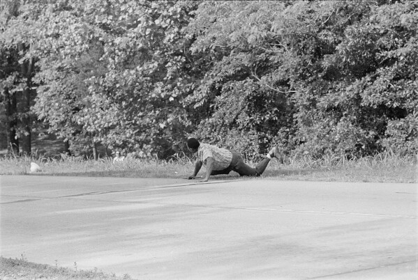 James Meredith looks at his would-be assassin, left, partially hidden behind foliage, after being shot down on a road near Hernando, Miss., June 6, 1966. (AP Photo/Jack Thornell, File)