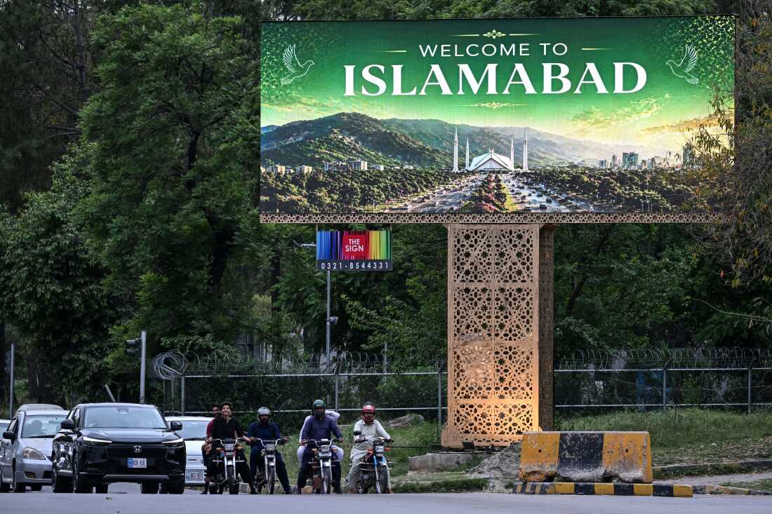 Commuters wait at a traffic signal beside a digital screen in Islamabad on Friday. Iran's foreign minister and U.S. envoys are expected to arrive in the city for possible peace talks.