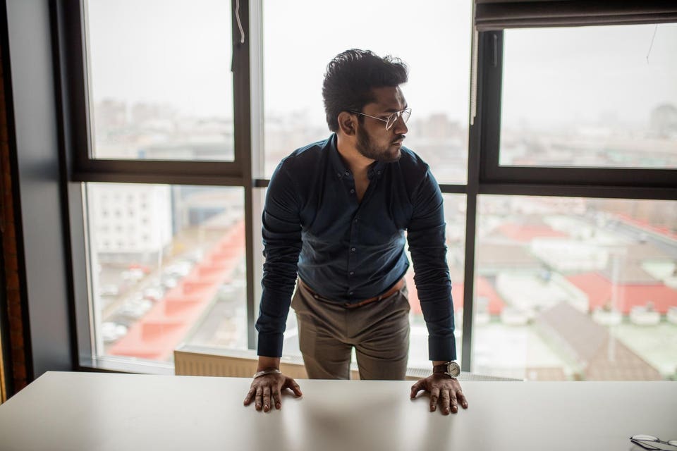 Portrait of a young Indian mam in spectacles posing agaist window