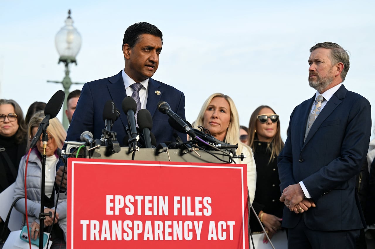 A person stands at a podium with several microphones behind a sign that says "Epstein files transparency act."