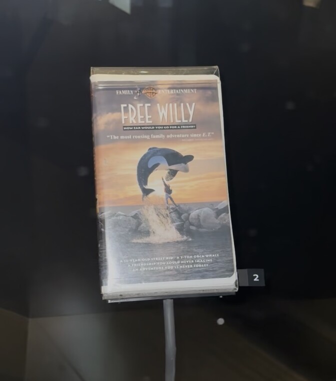 A VHS clamshell for the 1993 film 'Free Willy' depicts the famous scene of a killer whale jumping over a boy.