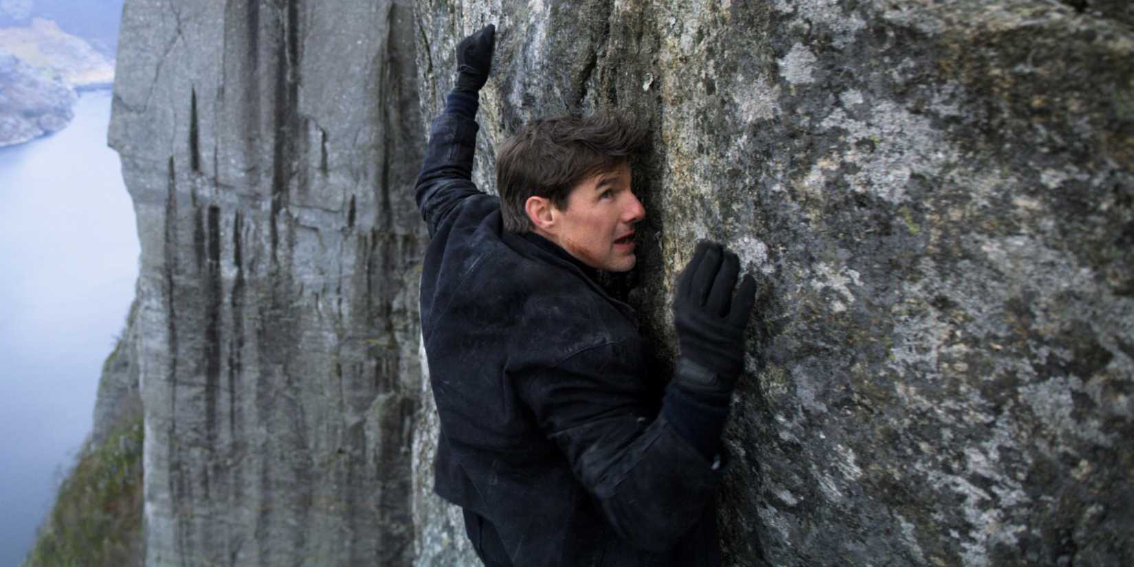 Tom Cruise as Ethan Hunt hanging off a cliff in Mission: Impossible – Fallout (2018)