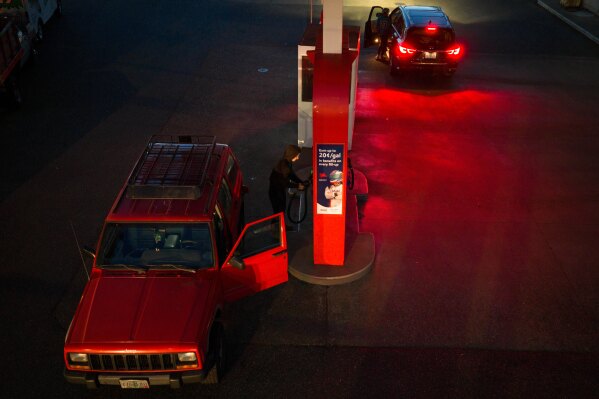 A person puts away a fuel nozzle after filling their gas tank at a Mobil gas station on Wednesday, April 29, 2026, in Portland, Ore. (AP Photo/Jenny Kane)