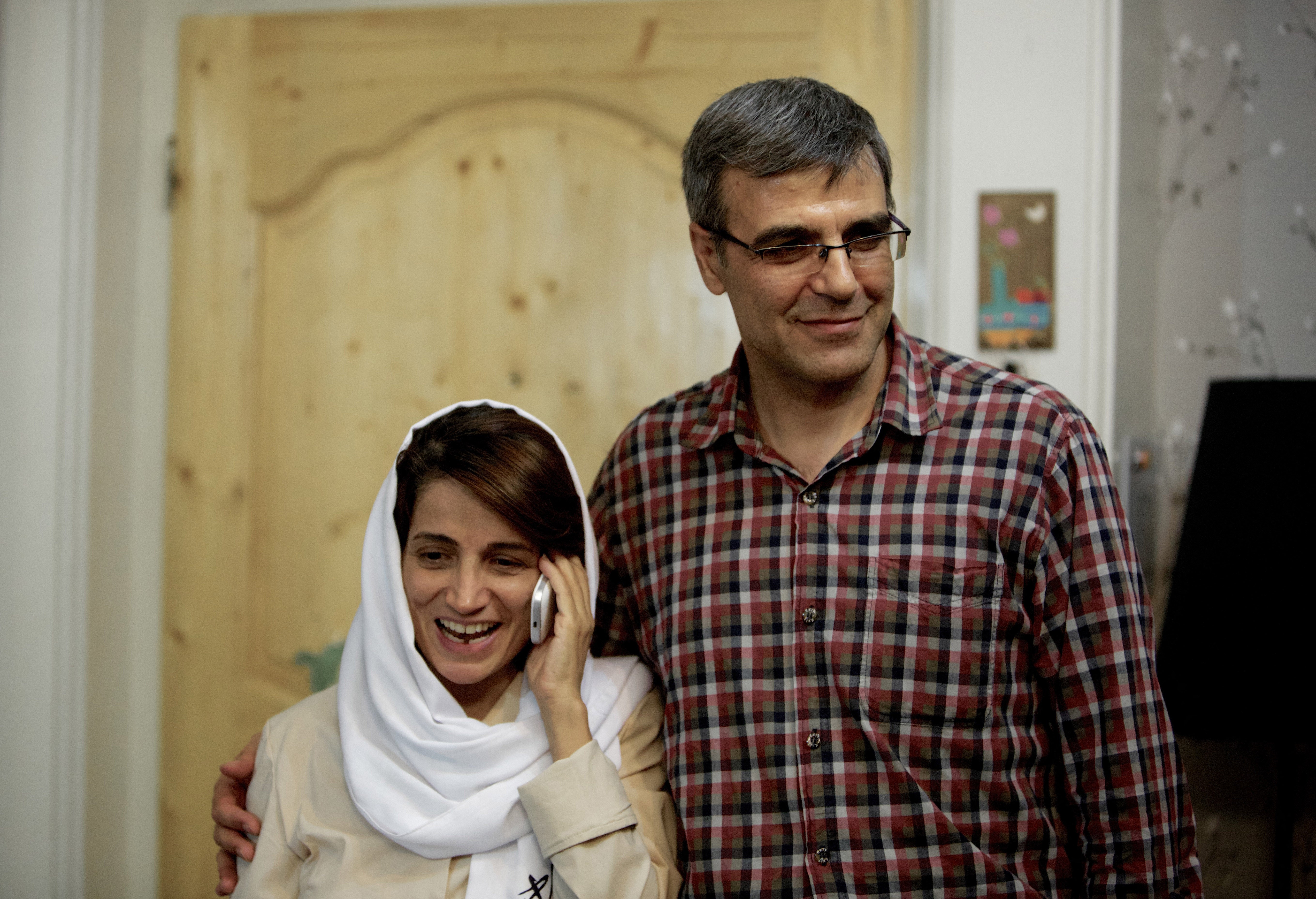 Iranian lawyer Nasrin Sotoudeh (L) speaks on the phone next to her husband Reza Khandan as they pose for a photo at their house in Tehran in 2013, after she was freed following three years in prison