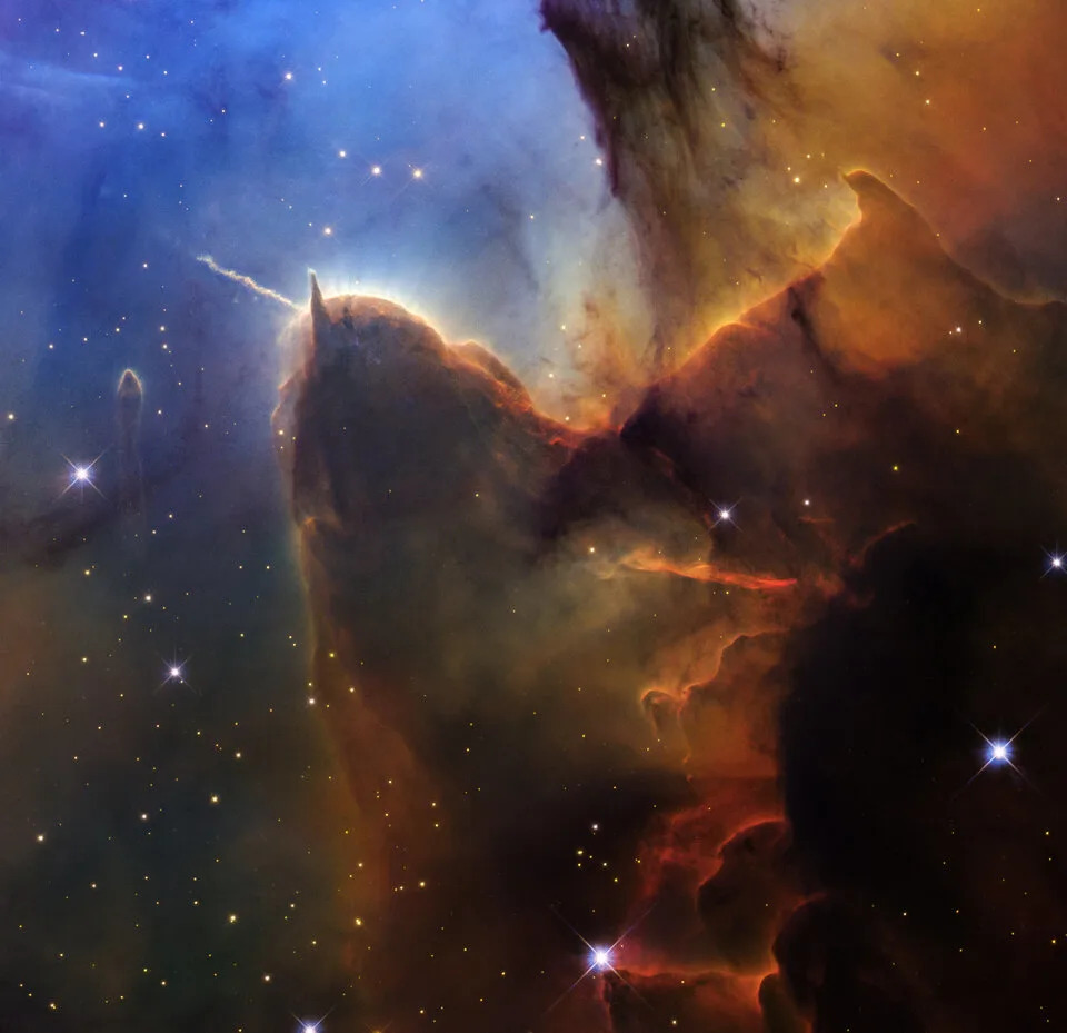 Swirling clouds of brown dust and gas mix in front of a starry blue spacescape