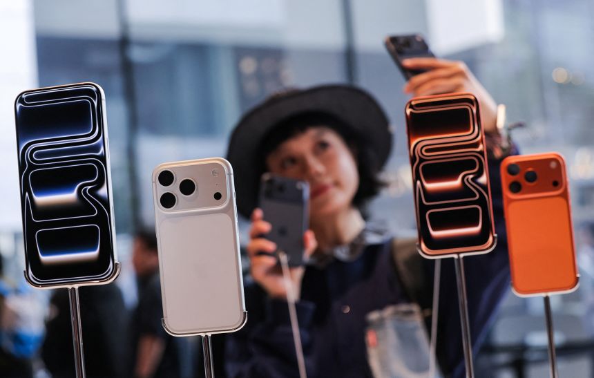 A woman takes a selfie with iPhones inside the Apple store in Beijing's Sanlitun area as the new iPhone 17 series smartphones go on sale in Beijing, China, on September 19, 2025.
