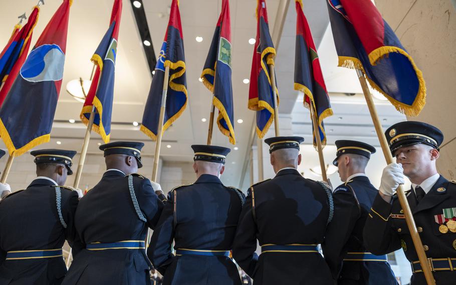 Soldiers hold flags as they march in.