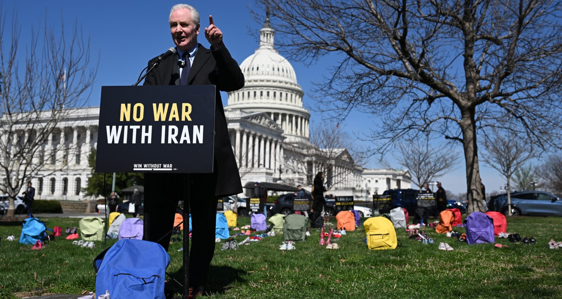 Sen. Chris Van Hollen (D-Maryland) speaks in front of a memorial made up of shoes and backpacks symbolizing those killed in the bombing of the Minab elementary school and other civilians killed in Iran sits outside the United States Capitol on March 18, 2026 in Washington, D.C.