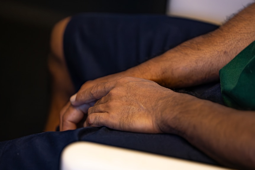 The hands of a man sitting down.