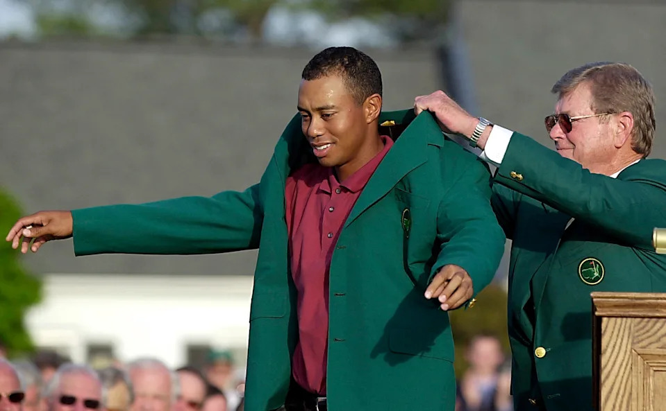 Tiger Woods (L) of the US gets his third green jacket from tournament chairman Hootie Johnson (R) 14 April 2002, after winning the 2002 Masters golf tournament at the Augusta National Golf Club in Augusta, GA. Woods finished the round one under par for a four day total of 12 under par. AFP PHOTO/ROBERTO SCHMIDT (Photo by Roberto SCHMIDT / AFP via Getty Images)