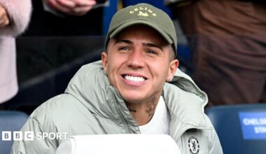 Enzo Fernandez smiling while in sat down in a Chelsea jacket
