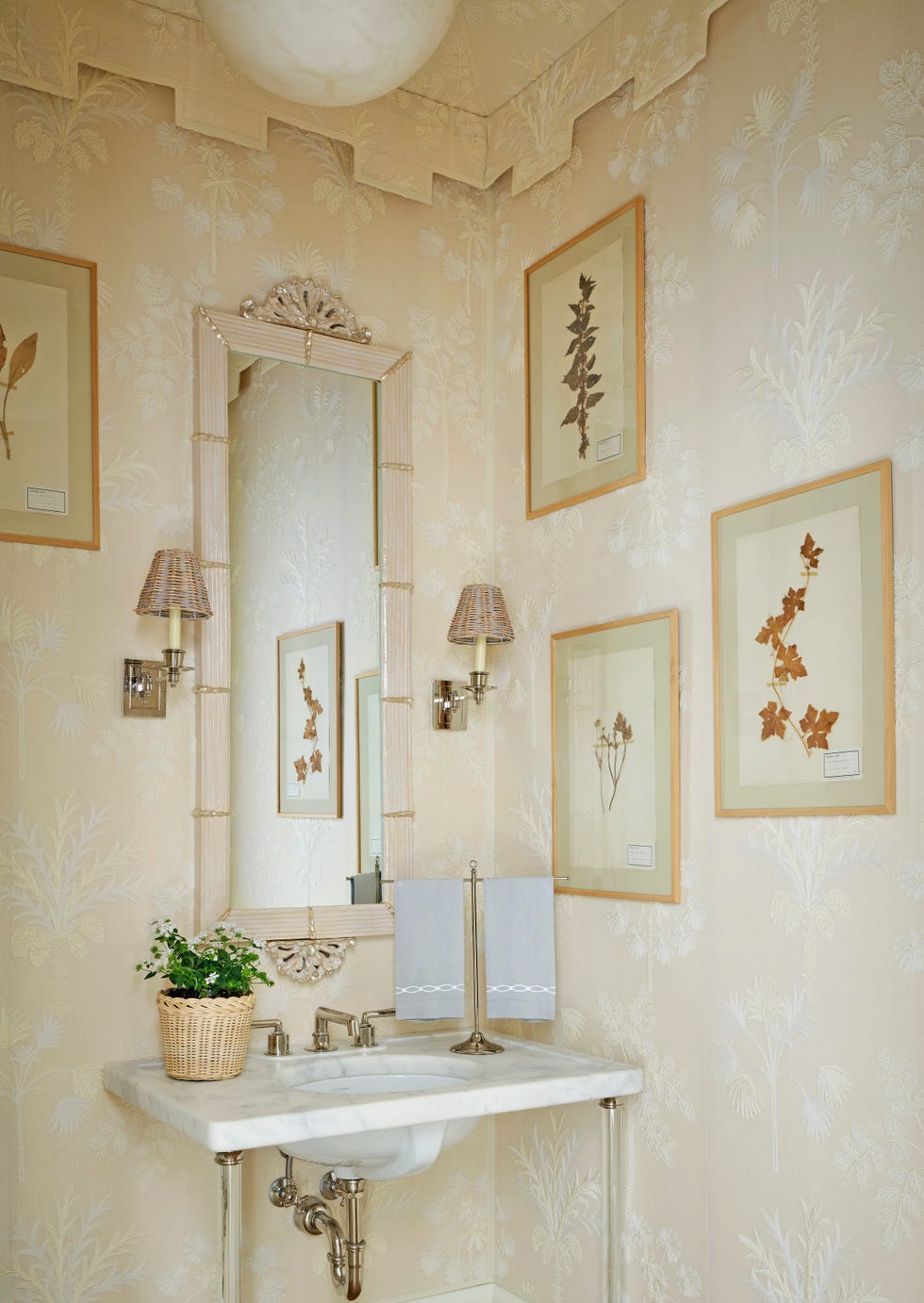 Powder room with floral wallpaper and framed botanical art.