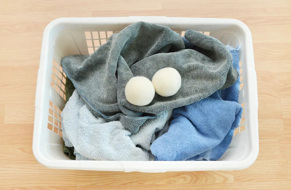 Basket with towels and two wool dryer balls, placed on a wooden floor