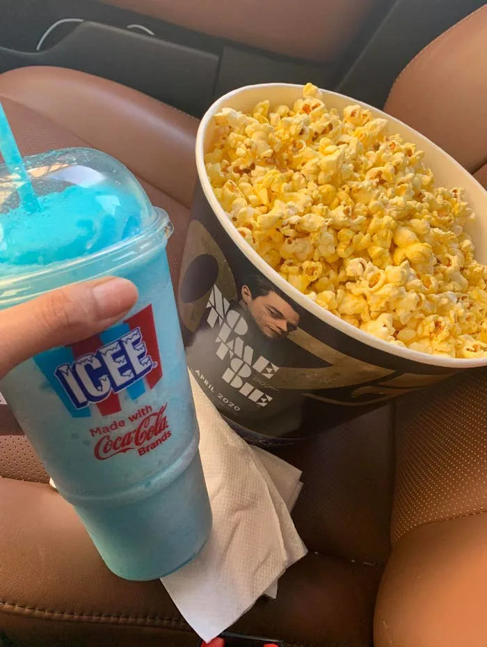 A cup of blue Icee and a large bucket of movie popcorn