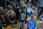 An Iranian worshipper wears a banner showing portraits of the Supreme Leader Ayatollah Mojtaba Khamenei, bottom, late Supreme Leader Ayatollah Ali Khamenei, top right, and the late revolutionary founder Ayatollah Khomeini, during Friday prayers ceremony at the Tehran University campus, in Tehran, Iran, Friday, April 24, 2026.
