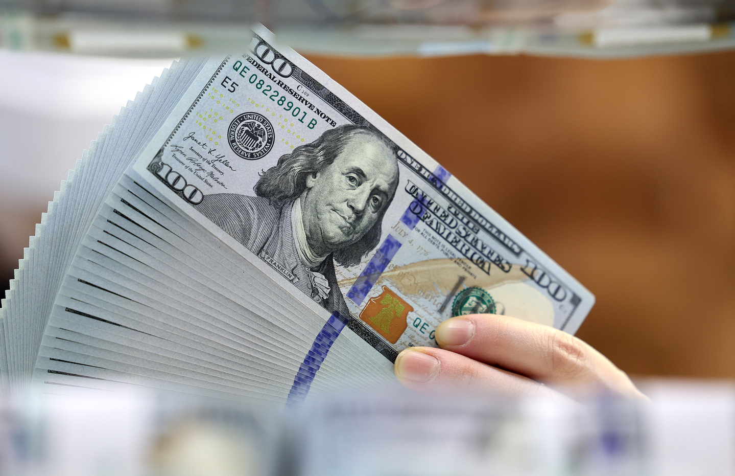 An employee holds up dollar bills at Hana Bank